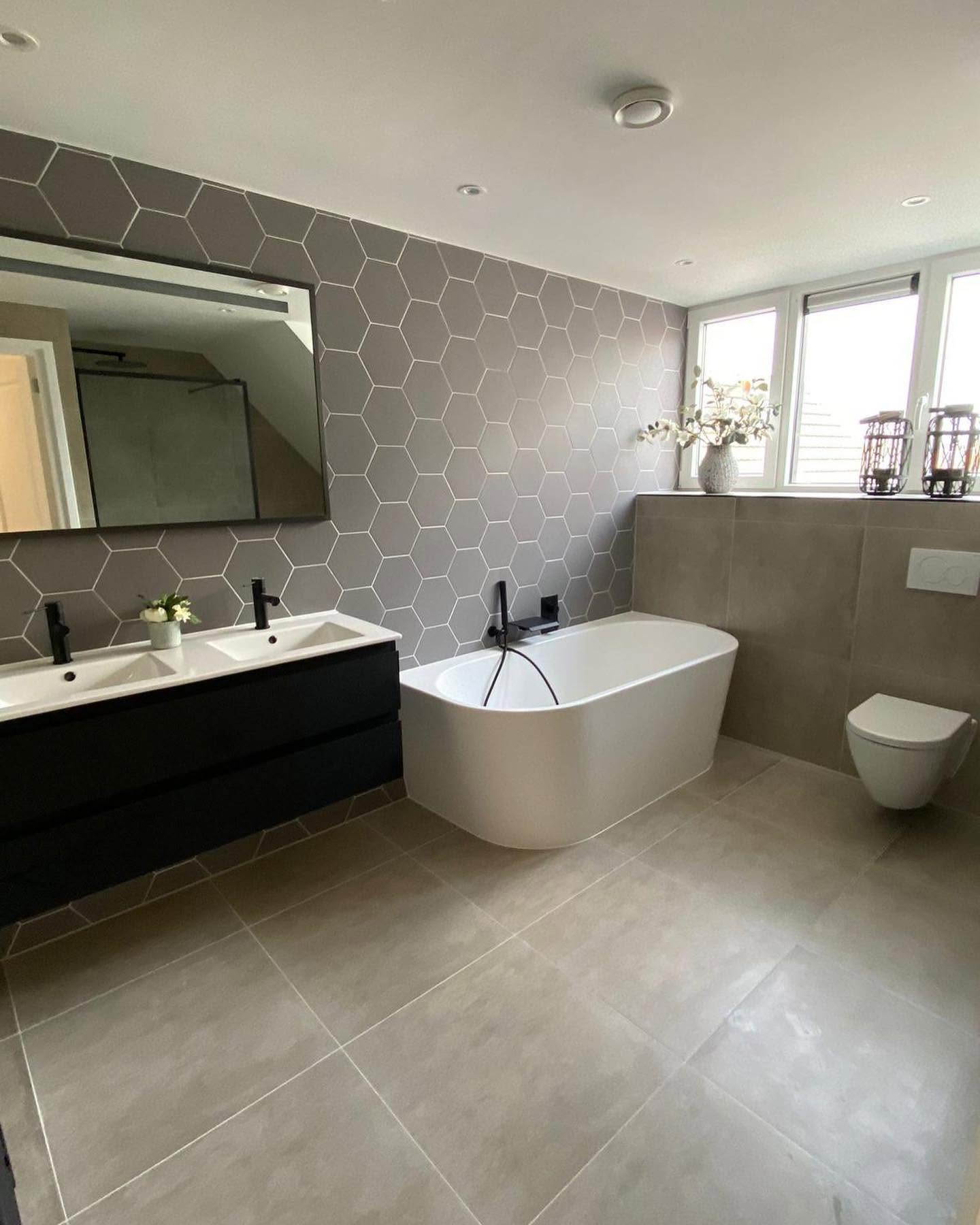 Lichte badkamer met bad, wastafel, douche en daglicht